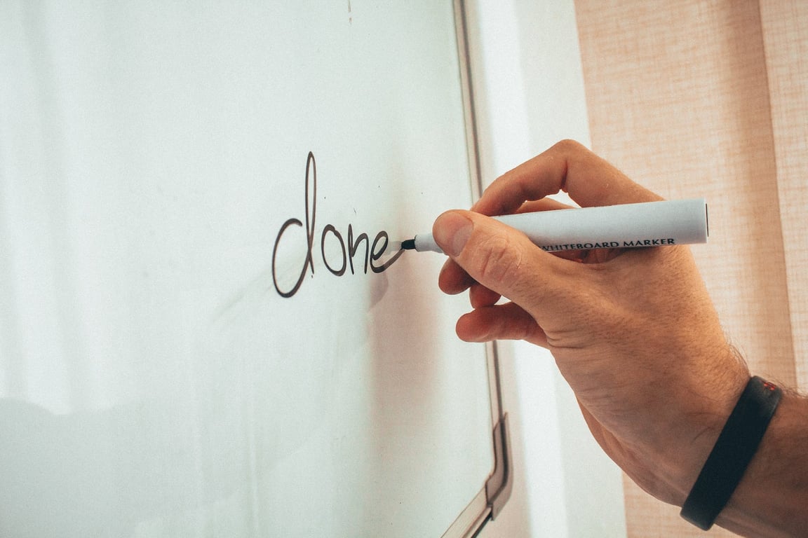 Un entraîneur masculin méconnaissable écrit un mot sur un tableau blanc pendant une présentation dans un bureau lumineux.